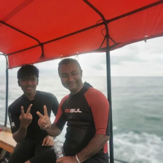 Deux hommes en combinaison de plongée sourient sur un bateau