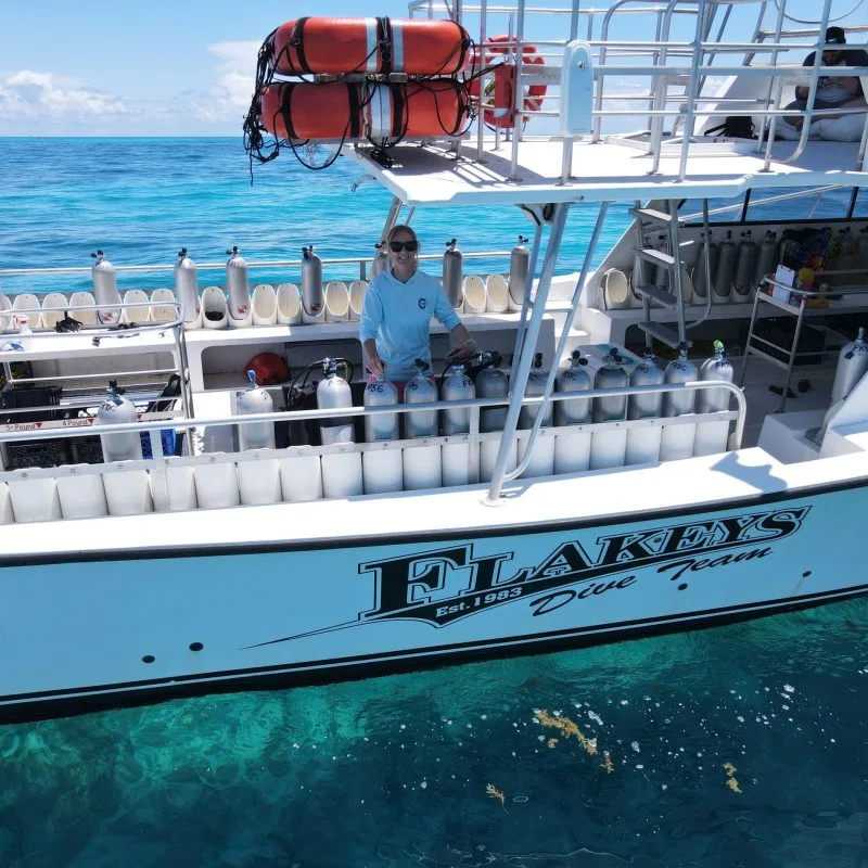 Bateau de plongée avec des bouteilles et un membre d'équipage souriant