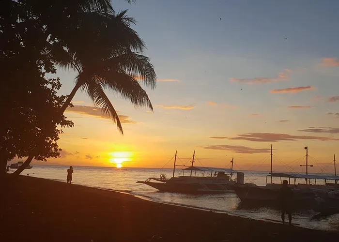 Coucher de soleil sur la plage avec des bateaux et une personne