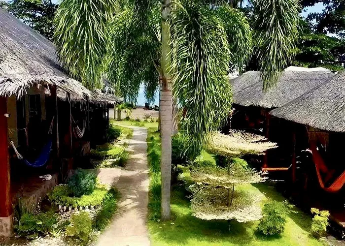 Allée bordée de bâtiments avec toits de chaume et végétation tropicale