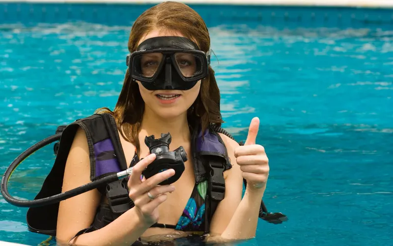 Jeune femme en équipement de plongée fait un signe positif