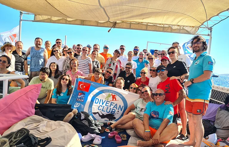 Groupe de personnes souriantes sur un bateau en mer, drapeau turc