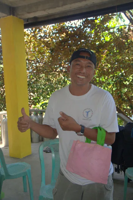 Un homme souriant fait un signe de pouce levé avec un sac