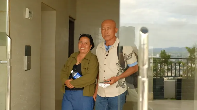 Deux personnes souriantes se tiennent devant une entrée vitrée