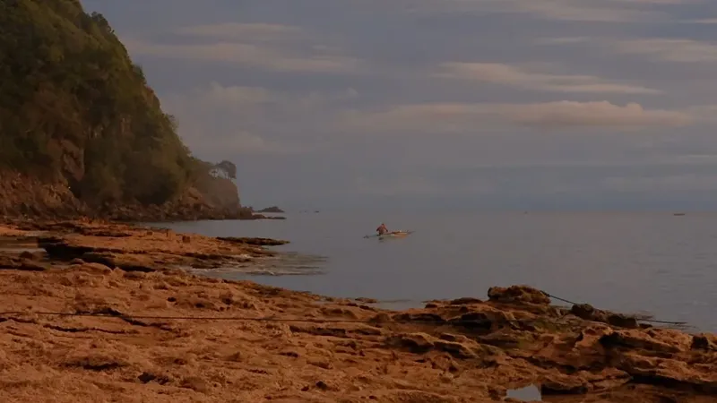 Personne sur une embarcation dans une baie rocheuse au lever du soleil