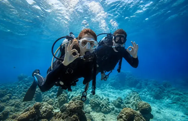 Deux plongeurs souriants font le signe OK sous l'eau