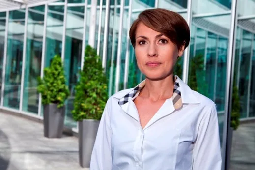 Portrait d'une femme regardant la caméra devant un bâtiment vitré