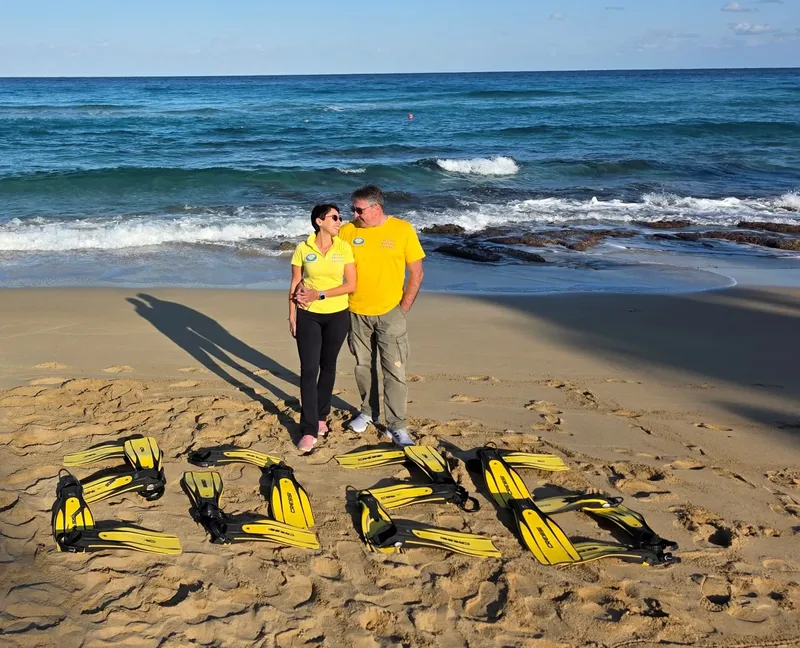 Deux personnes souriantes sur une plage avec des paires de palmes
