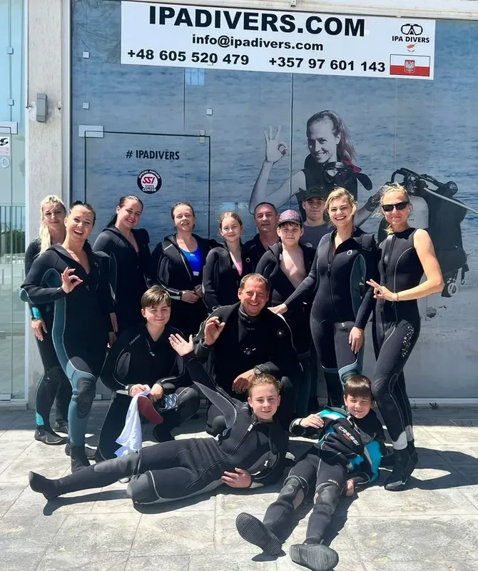 Groupe de plongeurs souriants posant devant une grande fresque marine