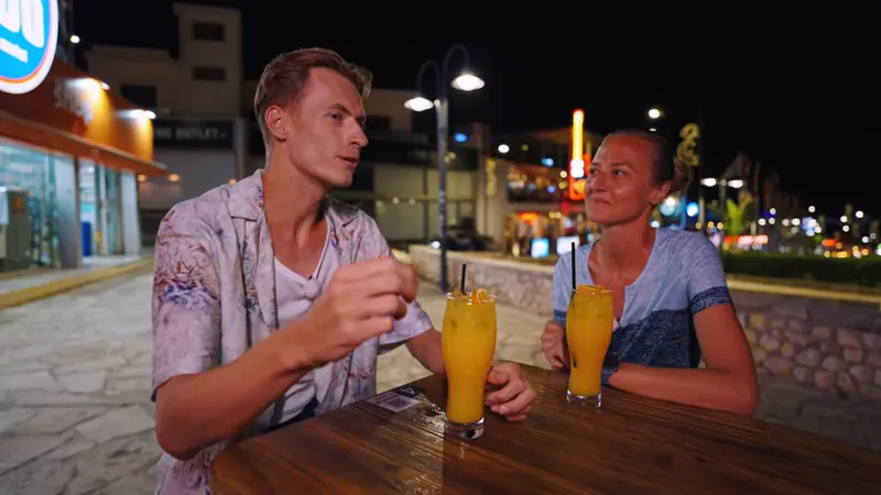 Deux personnes assises à une table boivent des jus d'orange