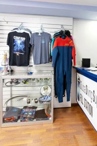 Boutique de plongée avec des combinaisons et t-shirts exposés sur des cintres