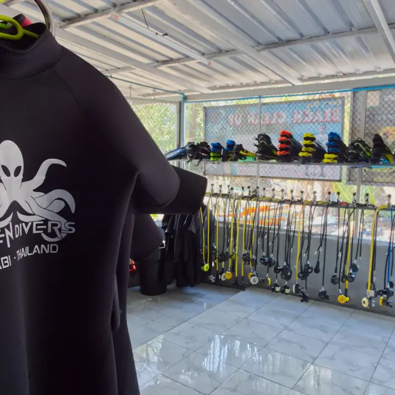 Combinaison de plongée noire avec logo, rangée de détendeurs et bouteilles