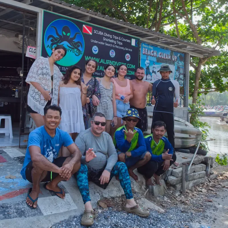 Groupe de personnes souriantes devant la facade d'un centre de plongée