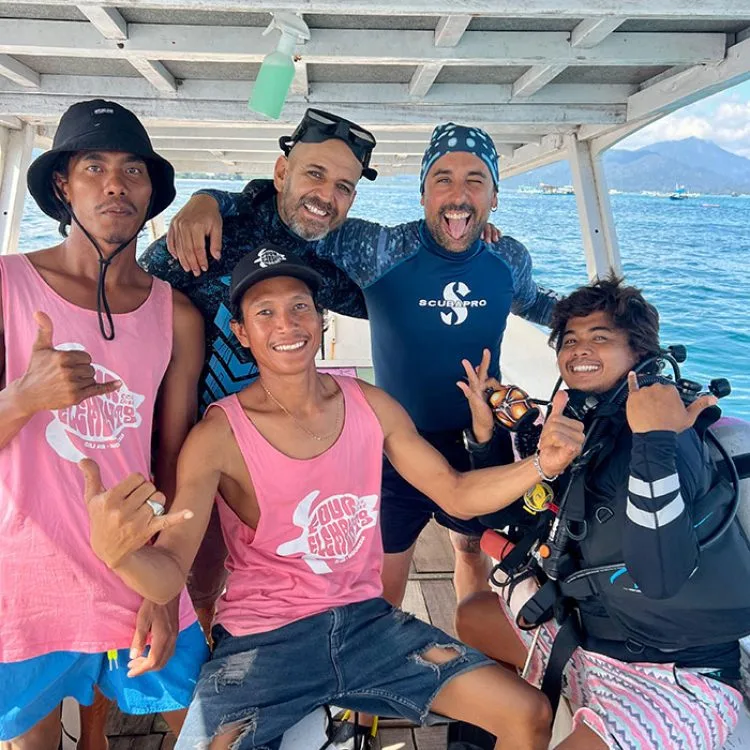 Quatre personnes souriantes sur un bateau, faisant des signes de validation