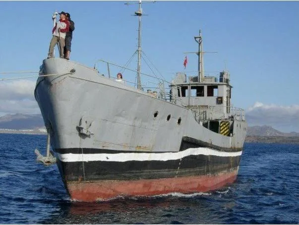 Bateau de plongée gris et noir en mer avec des personnes à bord