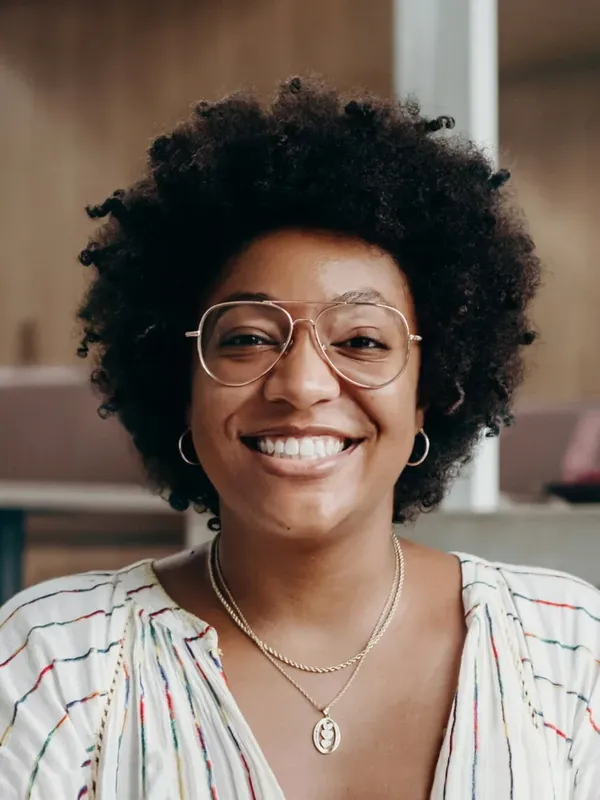 Portrait d'une jeune femme souriante avec des lunettes et des cheveux bouclés