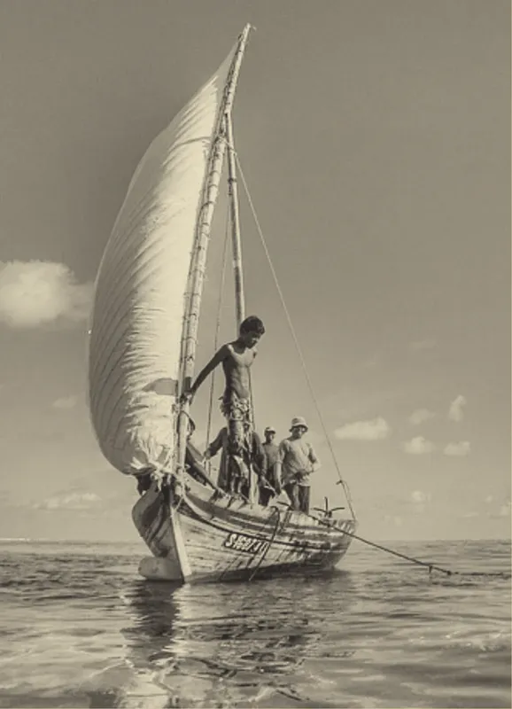 Plusieurs hommes à bord d'un bateau à voile traditionnel en mer