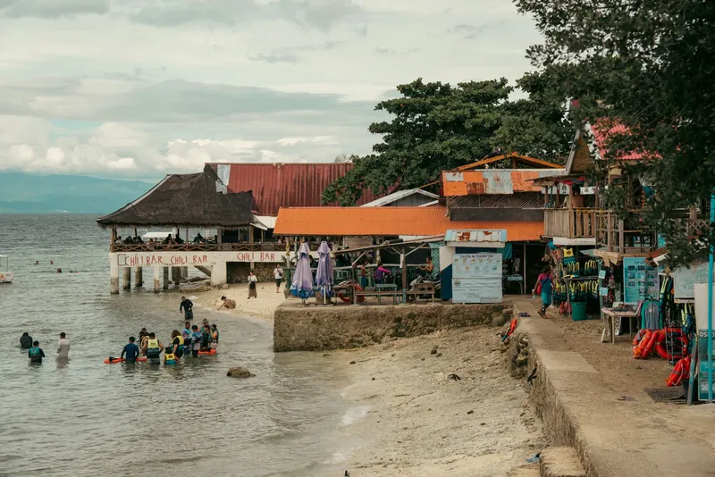 Plage avec centre de plongée, personnes entrant dans l'eau, bâtiments