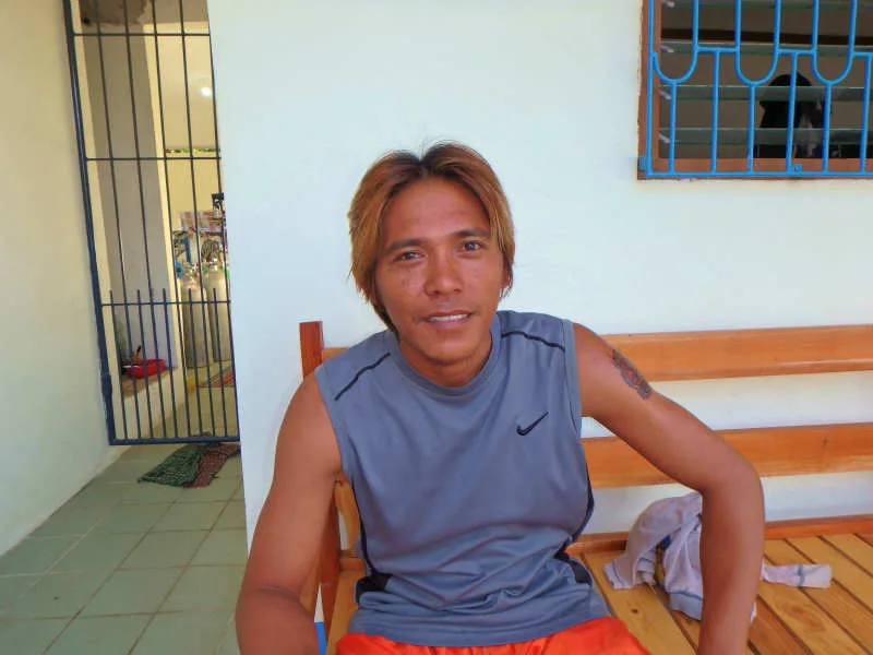 Un homme souriant est assis sur un banc en bois