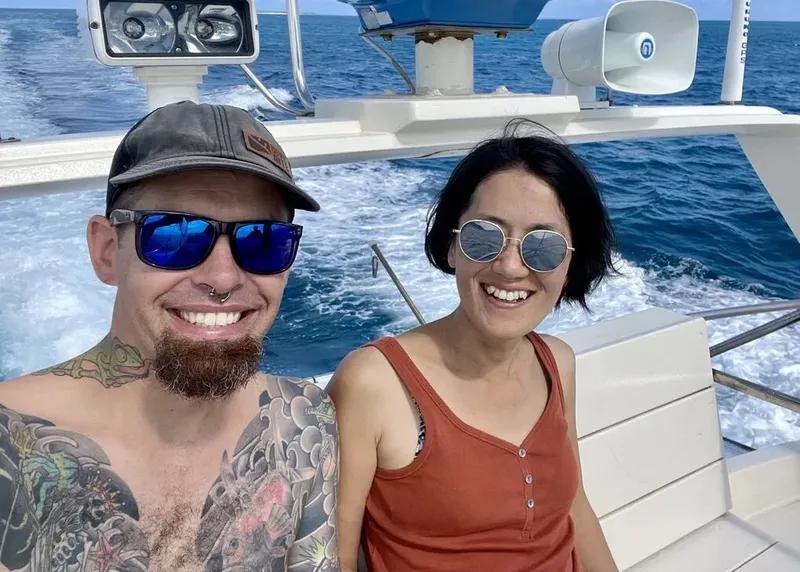 Deux personnes souriantes sur un bateau en mer, portant des lunettes