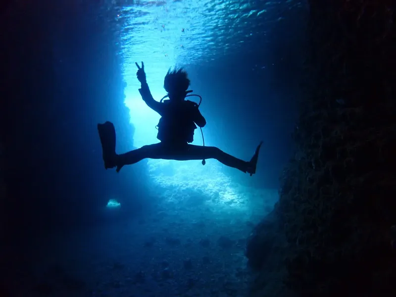 Plongeur silhouette sous l'eau, geste de la victoire, lumière ascendante