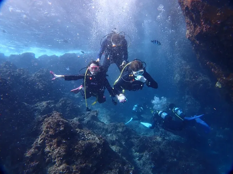 Plongeurs explorent un récif rocheux sous-marin avec de la lumière filtrante