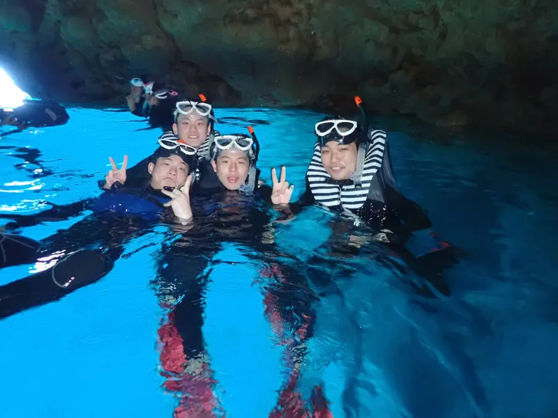 Groupe de plongeurs souriants dans une grotte sous-marine éclairée