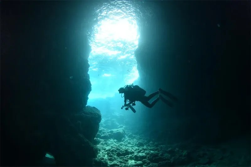 Plongeur explorant une grotte sous-marine avec une lumière vive