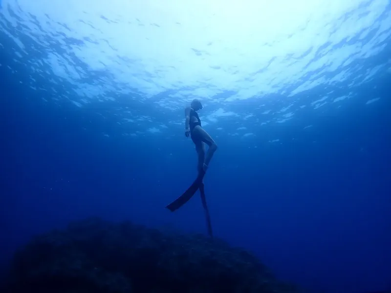 Apnée : une plongeuse en équilibre vertical dans l'eau bleue
