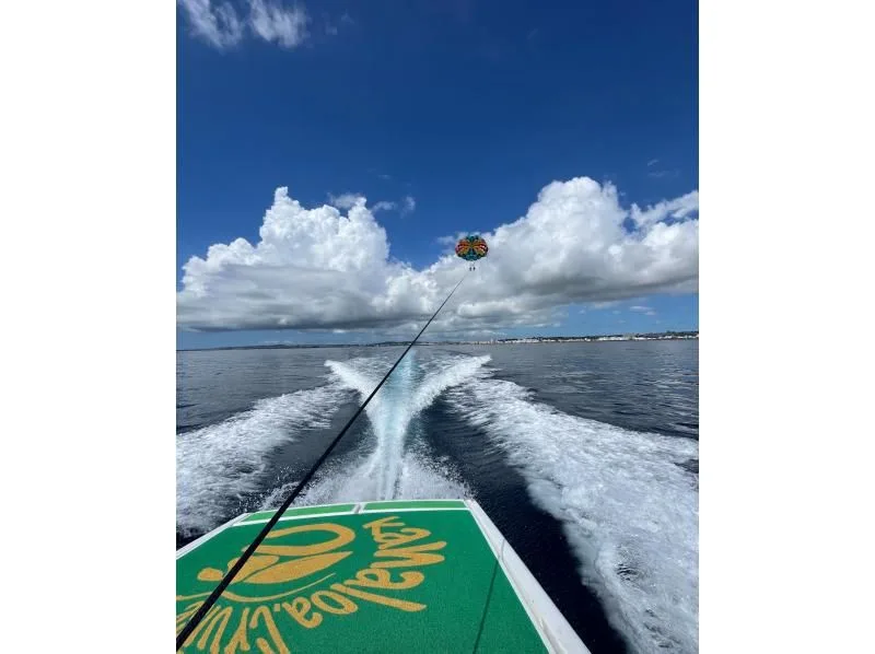 Bateau rapide en mer, sillage blanc, parasail dans le ciel bleu