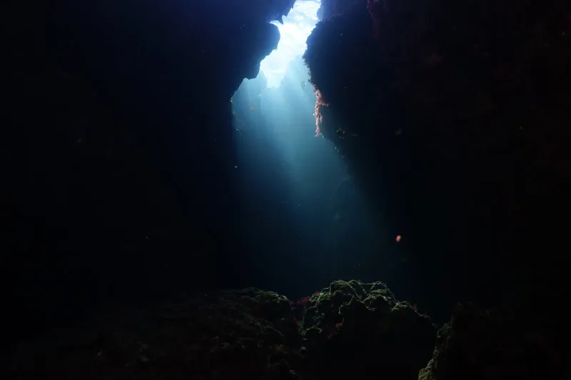 Rayons de soleil traversant une grotte sous-marine rocheuse et sombre
