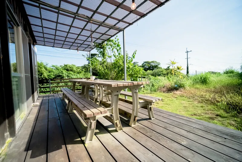 Terrasse en bois avec table et bancs devant un bâtiment et végétation