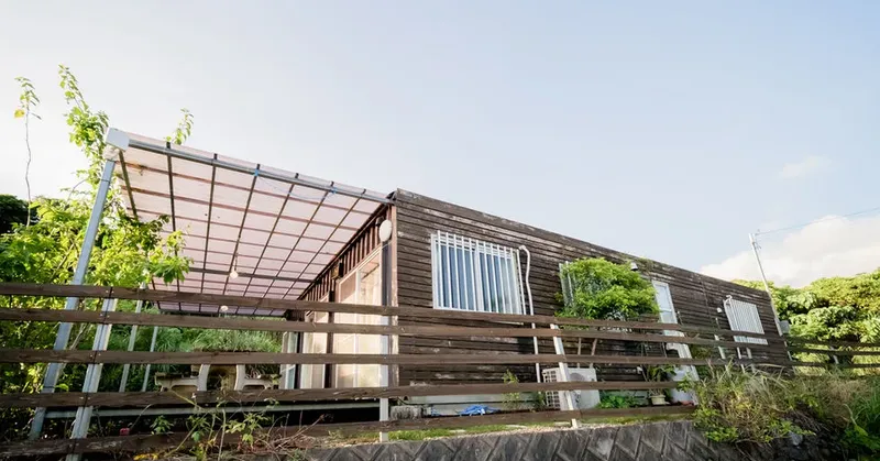 Bâtiment en bois avec auvent, végétation luxuriante et ciel bleu clair