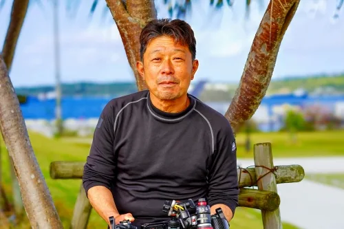 Homme asiatique souriant avec équipement de plongée en arrière-plan