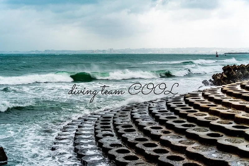Vagues déferlantes sur des brise-lames rocheux, ciel nuageux et texte