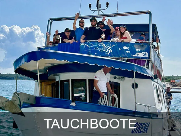 Groupe de personnes souriantes sur un bateau de plongée bleu et blanc