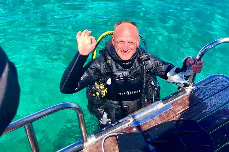 Plongeur souriant sortant d'un bateau avec un signe OK