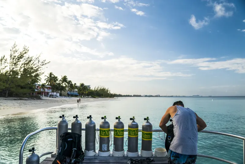 Bouteilles de plongée sur un bateau avec une personne préparant son équipement