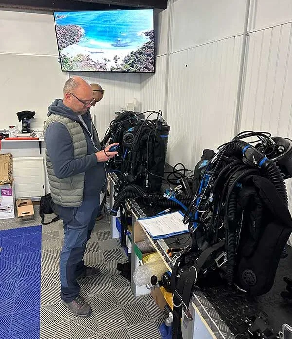 Un homme examine du matériel de plongée dans un local technique