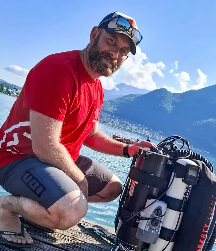 Plongeur souriant avec son équipement au bord de l'eau ensoleillée