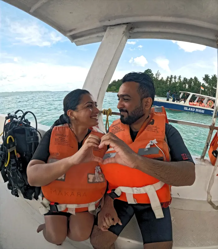 Couple souriant sur un bateau de plongée, équipés de gilets et bouteilles