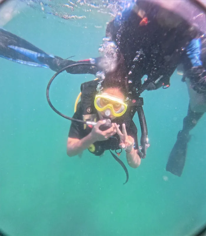 Deux plongeurs souriants en pleine eau, signe de paix