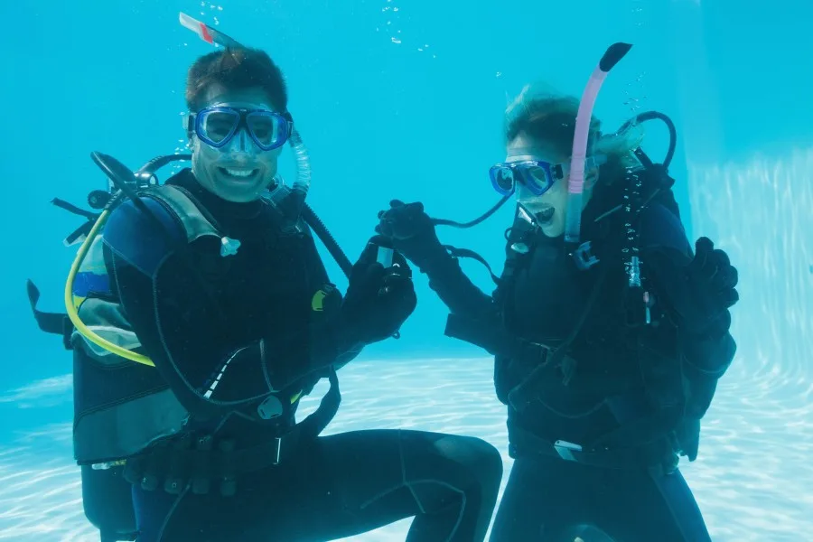 Deux plongeurs souriants se tiennent la main sous l'eau