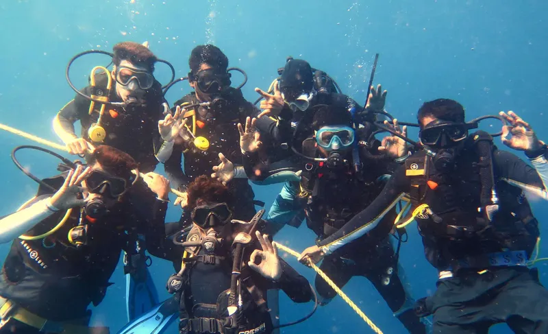Groupe de plongeurs souriants avec équipements complets sous l'eau
