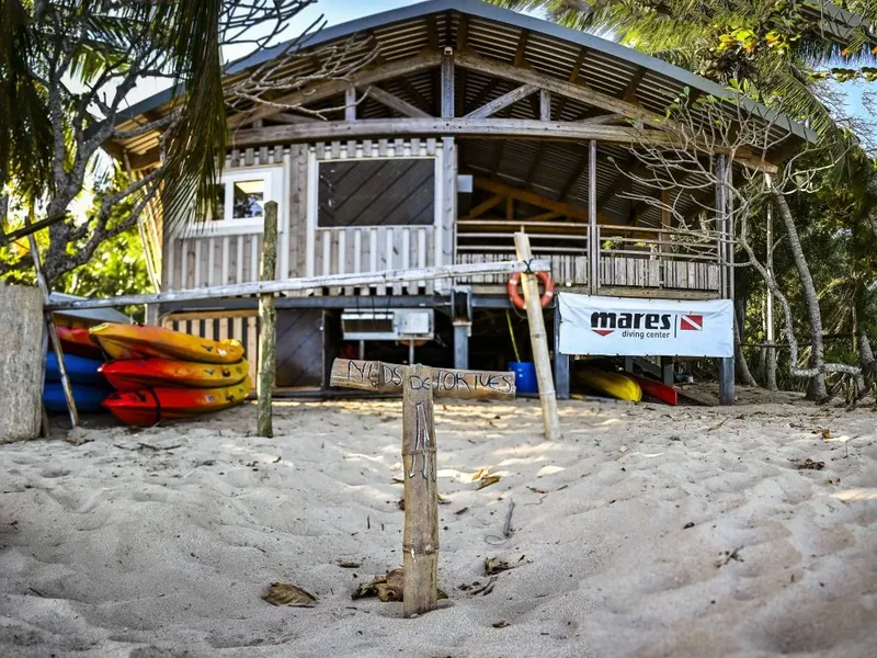Bâtiment de centre de plongée sur plage de sable avec kayaks et logo