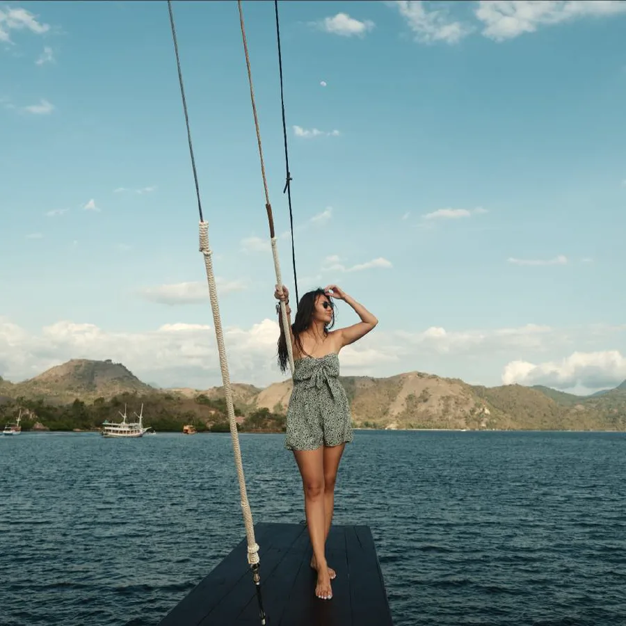 Jeune femme sur le pont d'un bateau en mer, paysage insulaire