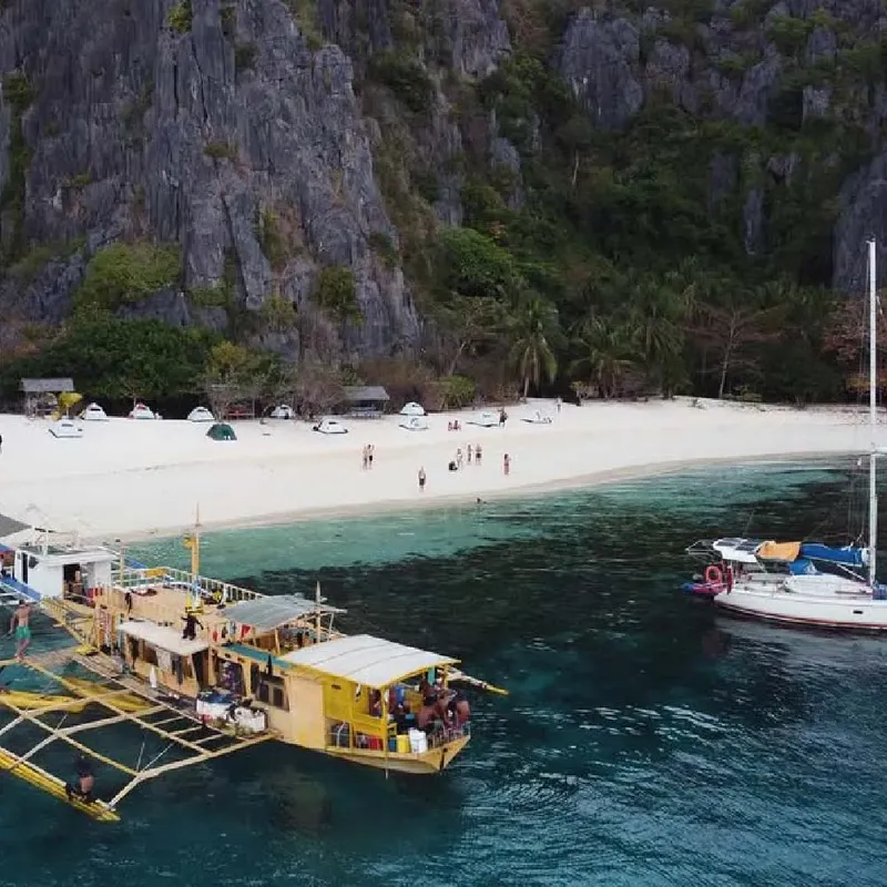 Plage de sable blanc avec bateaux et personnes se relaxant au soleil