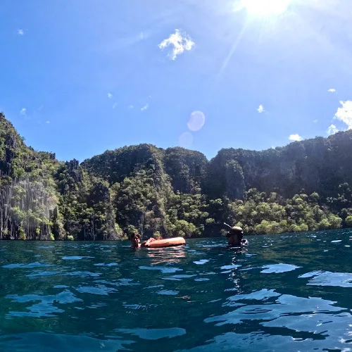 Plongeurs en surface dans une eau turquoise au milieu de falaises