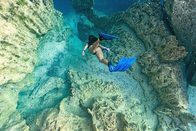 Plongeuse explorant un récif corallien avec des roches et du sable