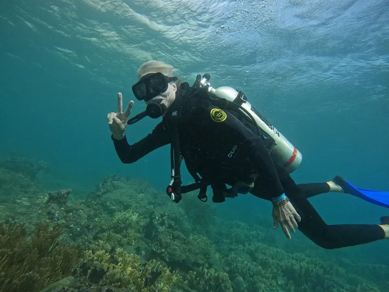 Plongeur souriant fait signe de la main sous l'eau en mer